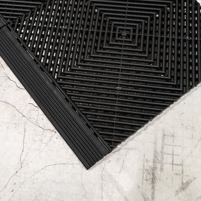 A closeup of Jet Black Swisstrax Ribtrax Pro tiles with a connecting ramp of the same colour