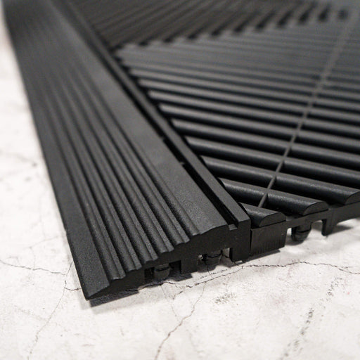 A side on view of connected Jet Black Swisstrax Ribtrax Pro ramps and tiles