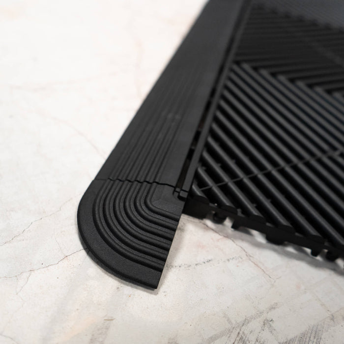 A closeup of a Ribtrax Pro Jet Black Corner attached on one side to a tile and ramp of the same colour