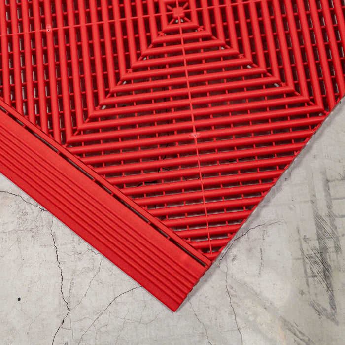 A closeup of a Racing Red Swisstrax tile connected to a ramp section of the same colour