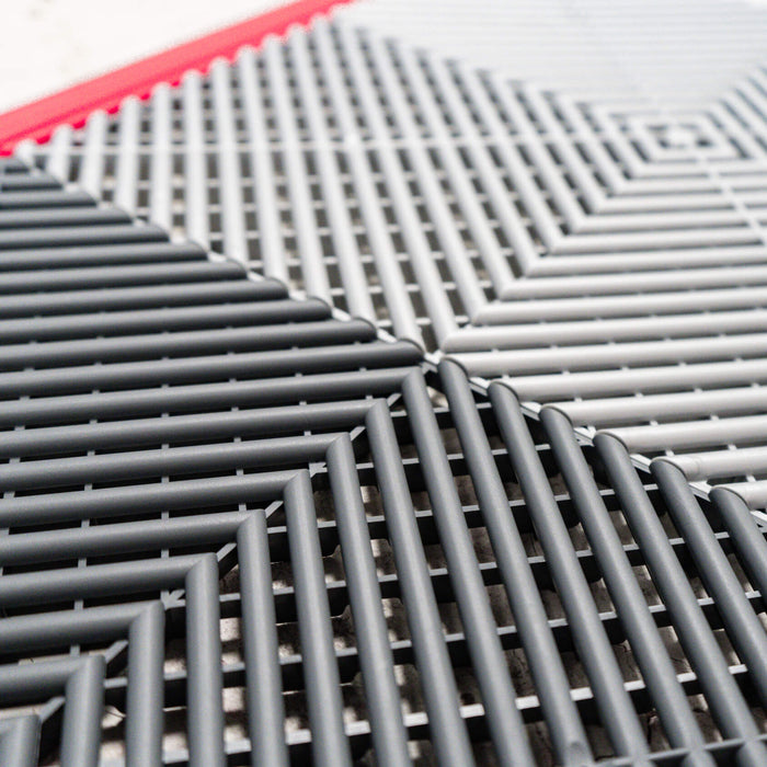 A closeup of connected Slate Grey and Pearl Silver Swisstrax tiles with Racing Red ramp sections