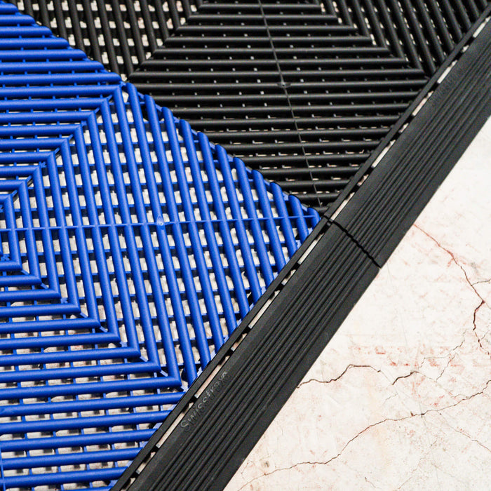 A closeup of connecting Royal Blue and Jet Black Swisstrax tiles with Jet Black ramp sections